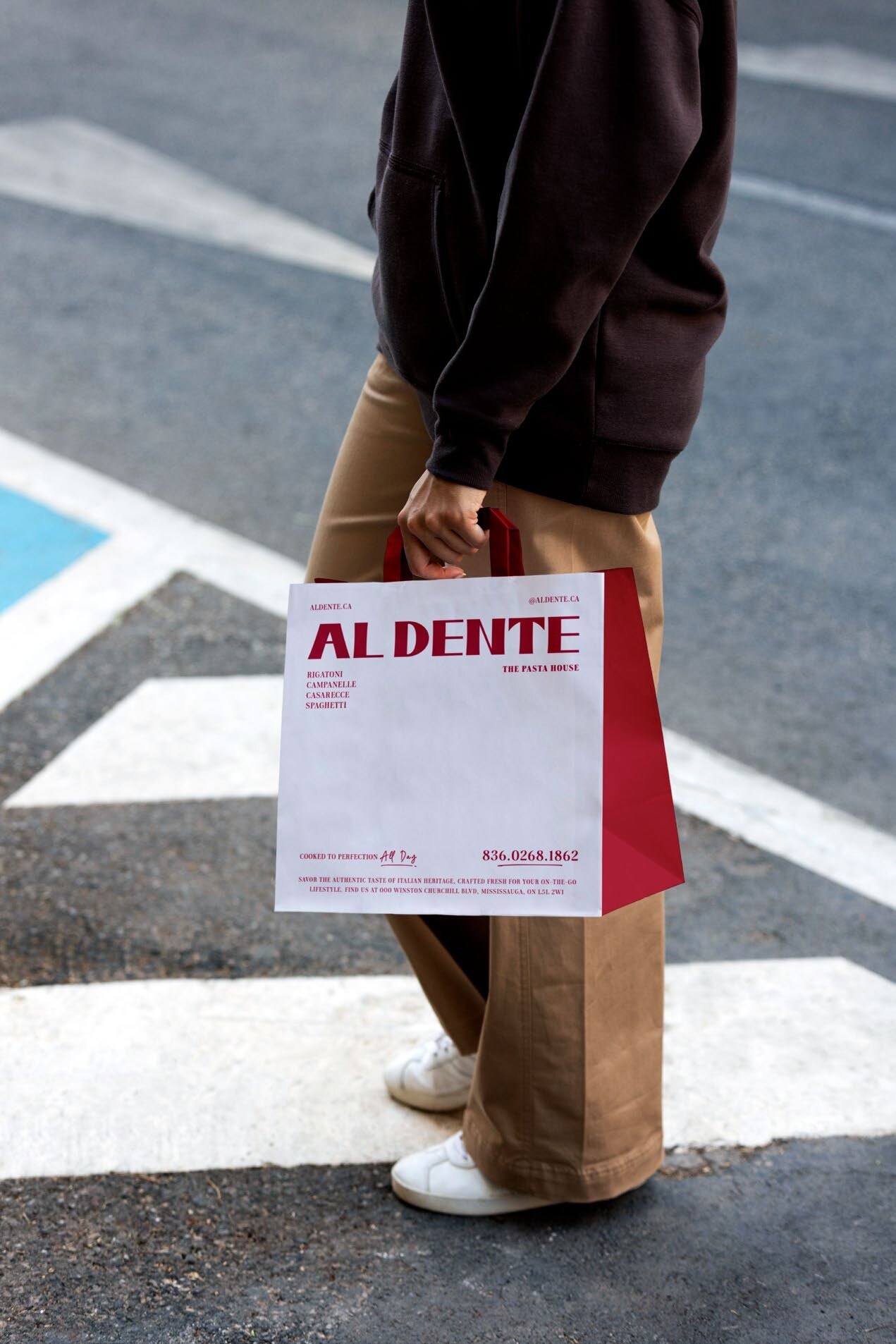 An Al Dente takeout bag carried across a crosswalk