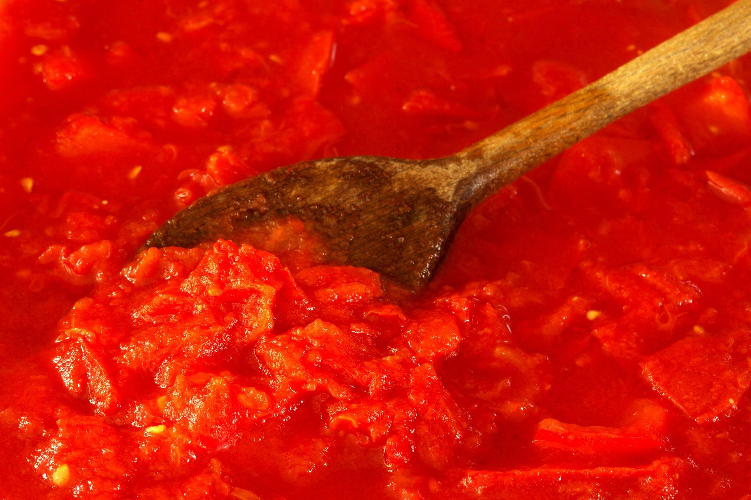 Fresh tomato sauce stirred with a wooden spoon